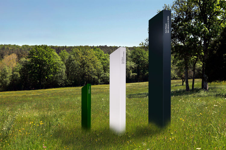 Trois monolithes Odyssées — bleu, blanc et noir — installés dans un pré