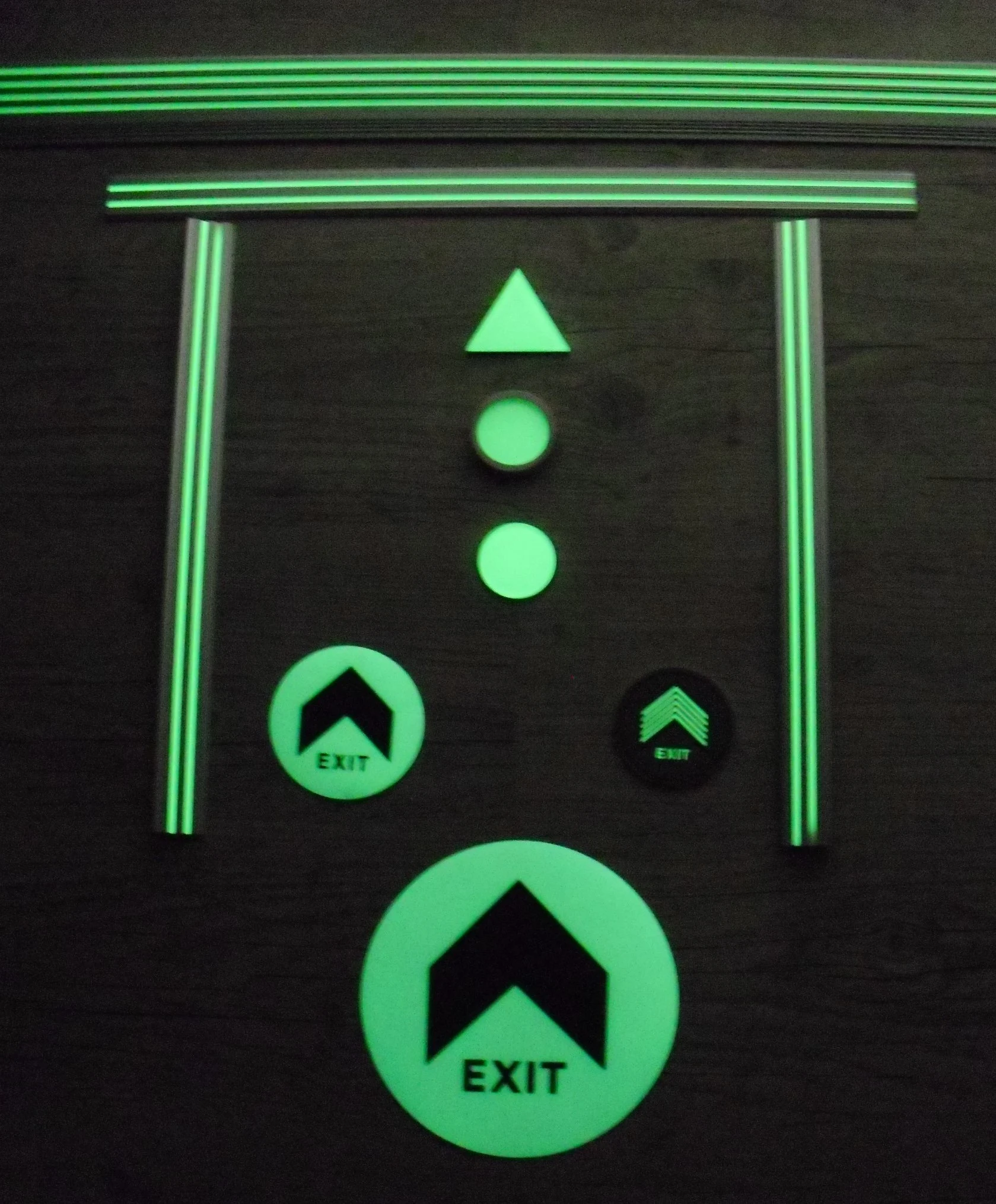Signalétique photoluminescente au sol d'un parking — flèches et balisage EXIT visibles dans l'obscurité